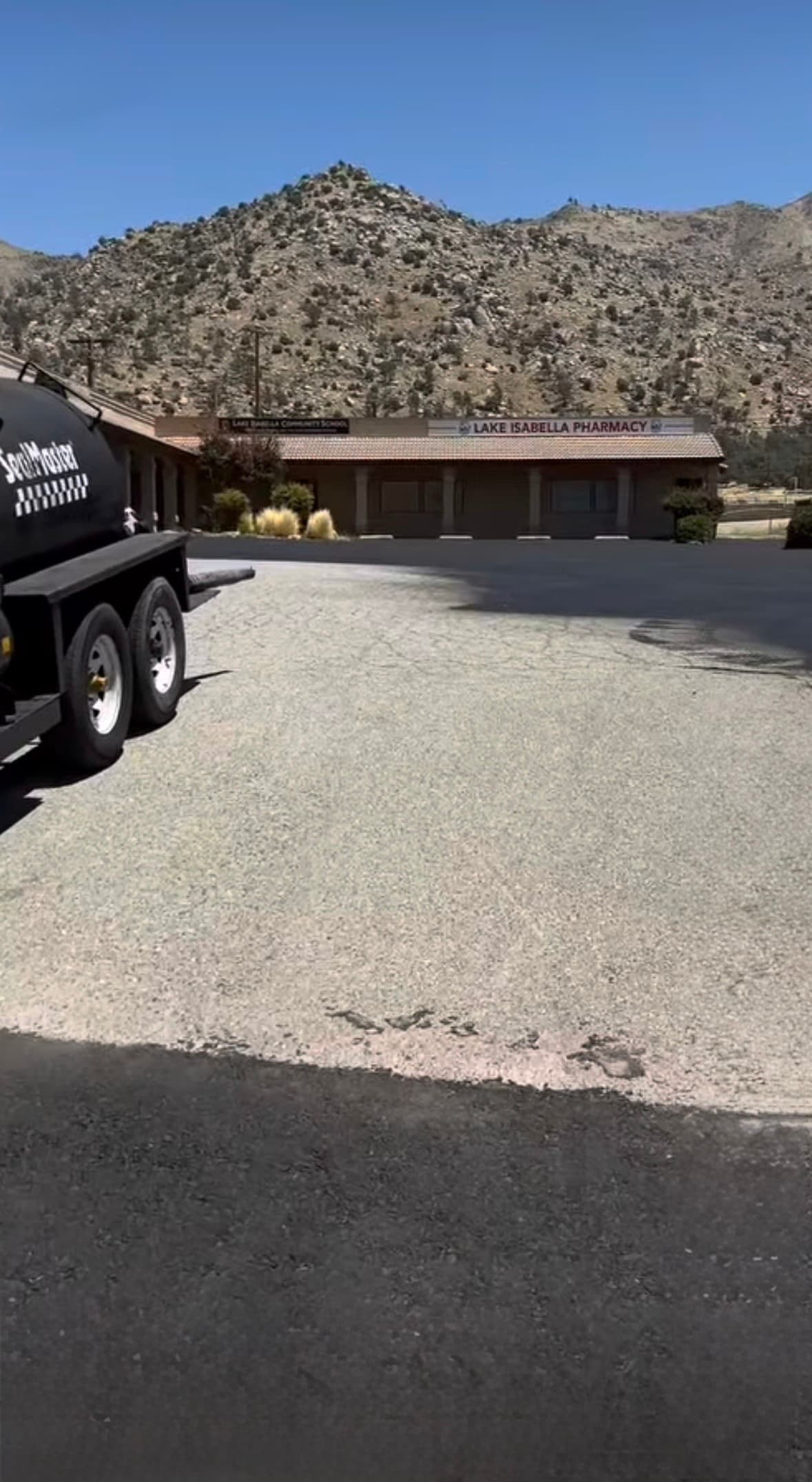 SealMaster trailer in a parking lot with Lake Isabella Pharmacy and mountains behind.